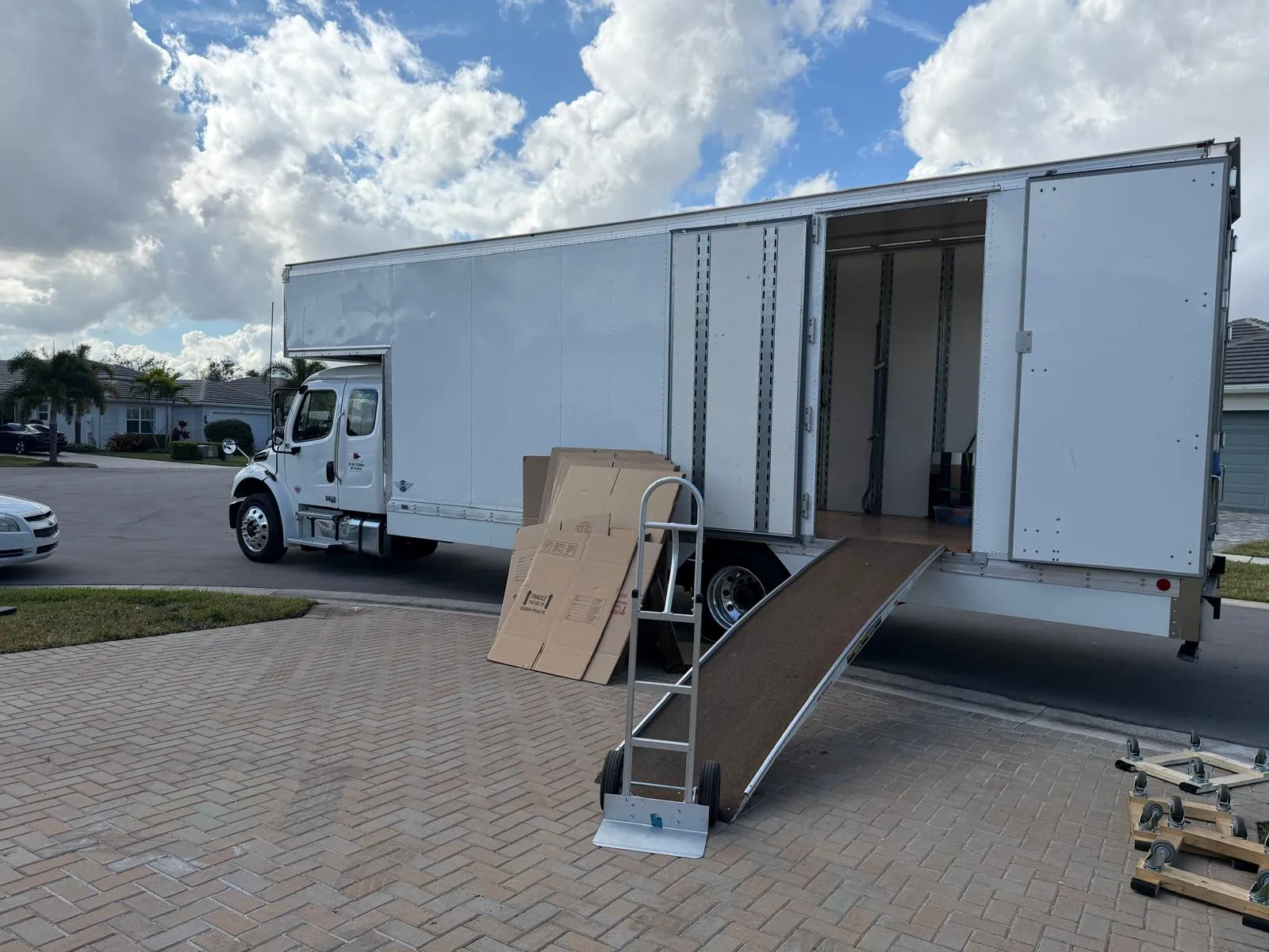 Atlantic Group USA moving truck with loading ramp and hand truck in a Florida driveway